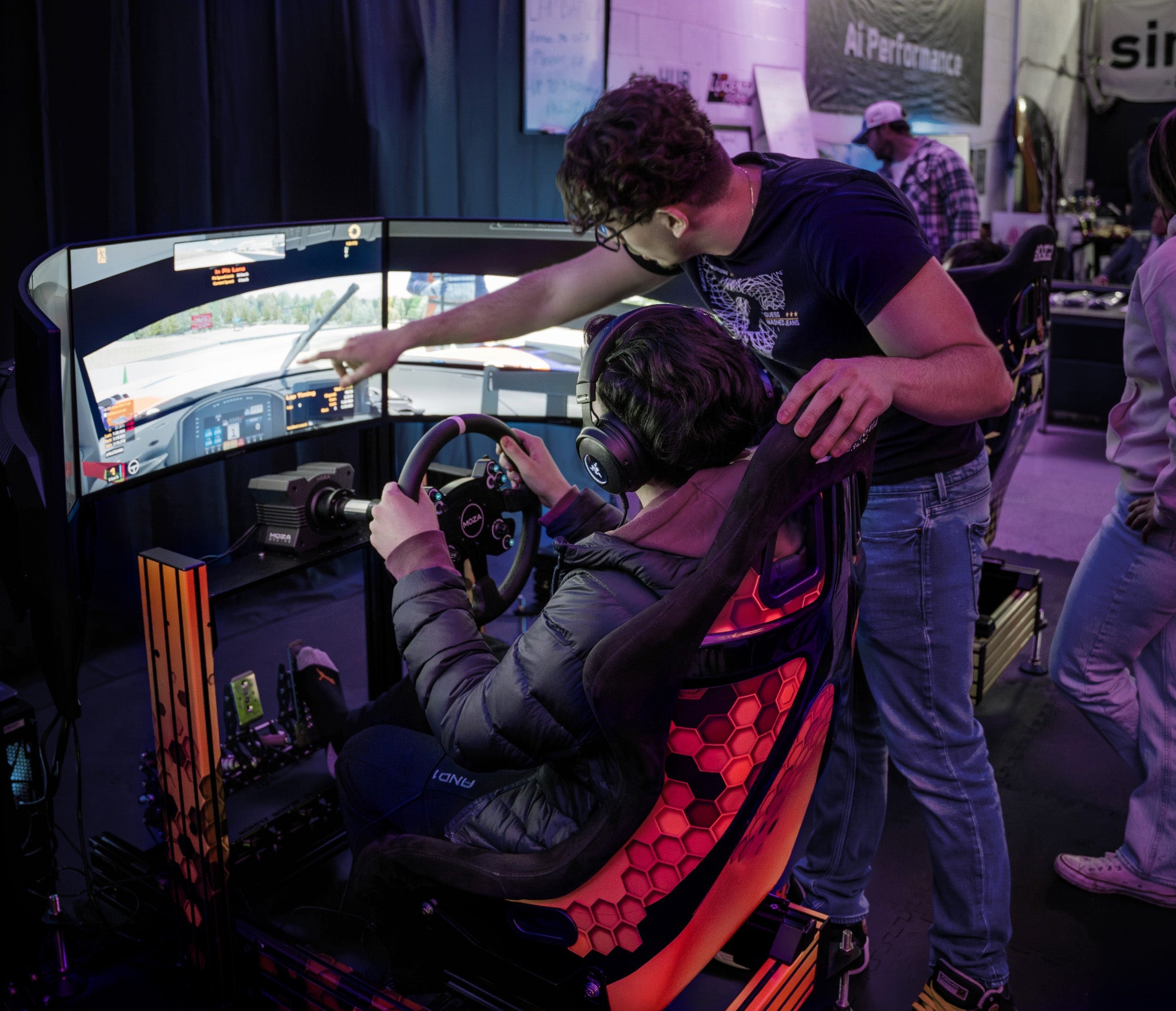Coaching a driver on a racing simulator with multiple monitors and steering wheel